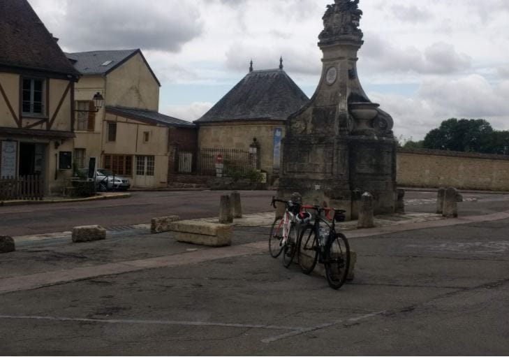 Bicycles parked near historic stone monument in village square.