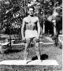 Man standing outdoors in swimwear, historical photo.