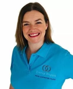 Smiling physiotherapist in blue Omnia Physio shirt.