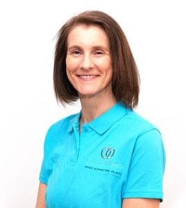Woman in blue uniform smiling against white background.