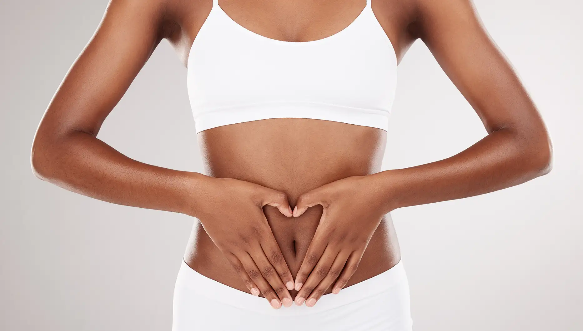Woman forming heart shape on stomach in white clothing