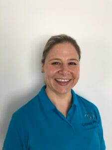 Smiling woman in blue Omnia Physio shirt.