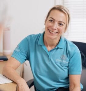 Smiling physiotherapist in blue shirt seated at desk